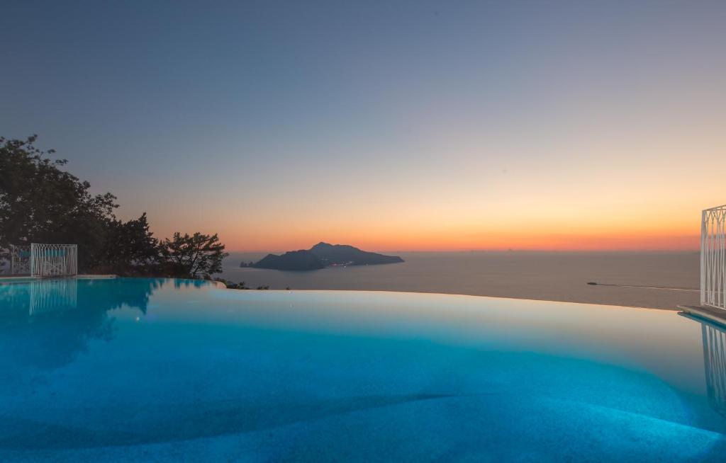 a swimming pool with a sunset in the background at Relais Blu in Massa Lubrense