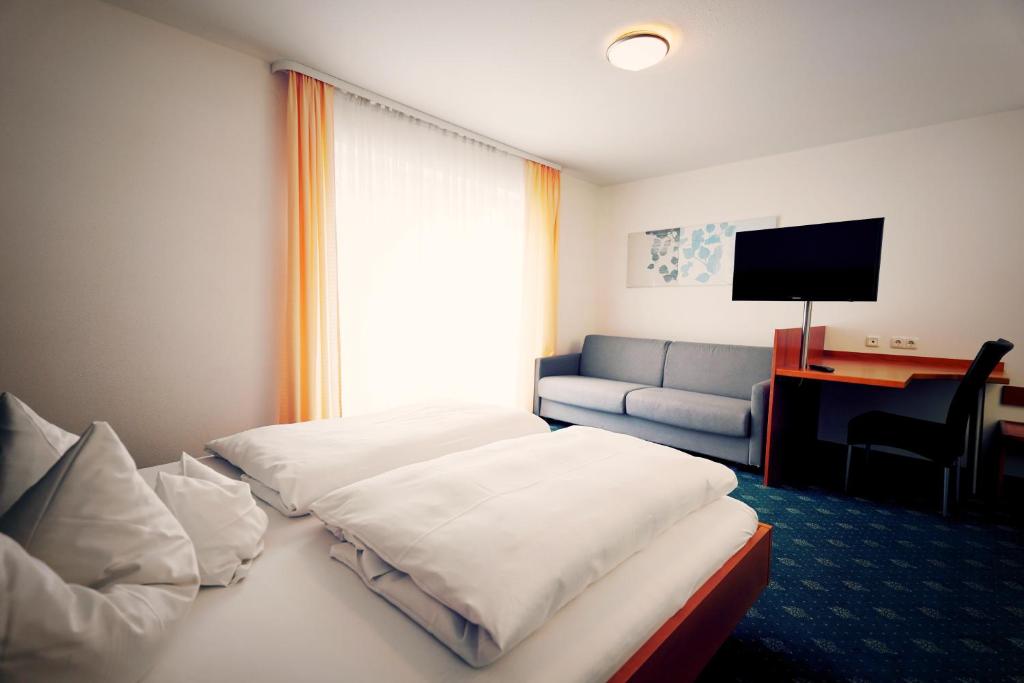 ein Hotelzimmer mit einem Bett und einem Sofa in der Unterkunft Grüner Baum Garni in Krumbach
