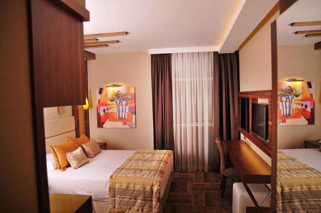 イズミールにあるAvin Hotelのベッド2台とデスクが備わるホテルルームです。