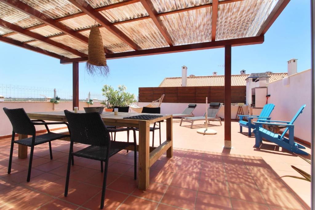 a patio with a wooden table and chairs on a roof at Penthouse Alentejana in Vila Nova de Milfontes
