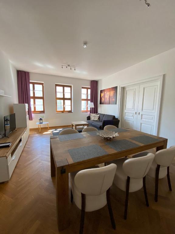 grosszügiges Apartment mit Blick zur Frauenkirche في درسدن: غرفة معيشة مع طاولة وكراسي خشبية