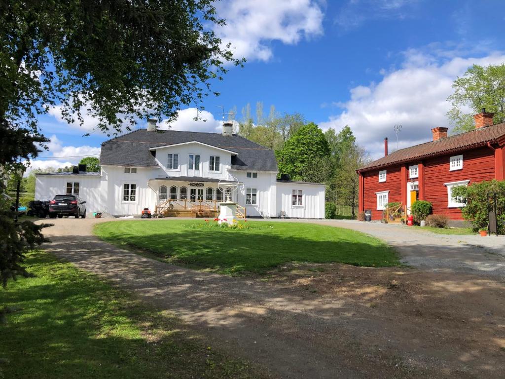 ein großes weißes Haus mit einer roten Scheune in der Unterkunft Bredsjö Gamla Herrgård White Dream Mansion in Hällefors