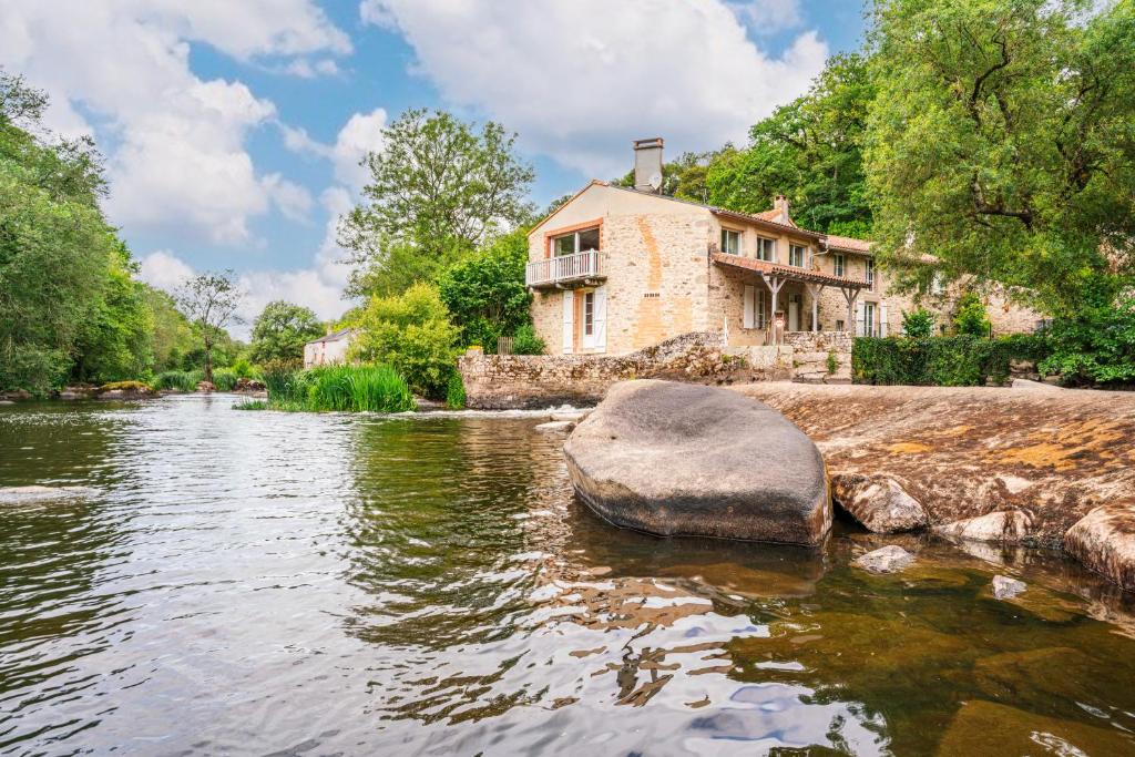 une maison en pierre assise sur le bord d'une rivière dans l'établissement Le Moulin de Pilet, à Mortagne-sur-Sèvre