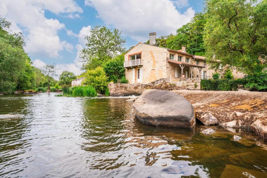 a stone house sitting on the side of a river at Le Moulin de Pilet in Mortagne-sur-Sèvre