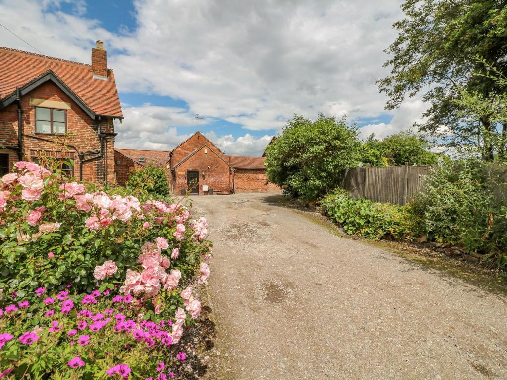 a dirt road in front of a house with flowers at The Cottage in Mapperley
