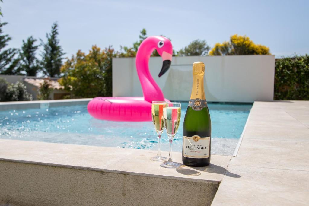 a bottle of champagne and two glasses next to a flamingo at Les Villas des Fontaines in Saumane-de-Vaucluse