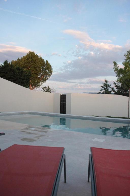 a swimming pool in front of a white wall at Les Villas des Fontaines in Saumane-de-Vaucluse