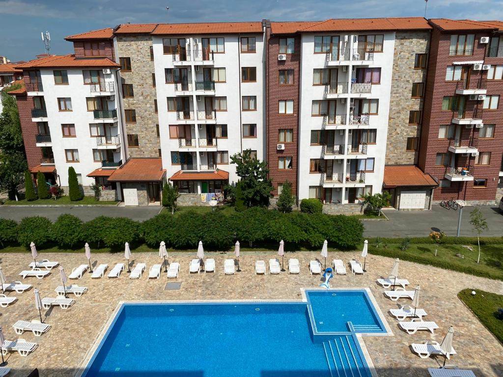een hotel met een zwembad en stoelen en een gebouw bij Apolon - beautiful apartments 200 m to the beach in Ravda