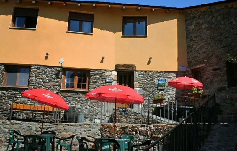 ein Gebäude mit roten Sonnenschirmen vor einem Gebäude in der Unterkunft Casa Rural La Fuente in Tejedo del Sil