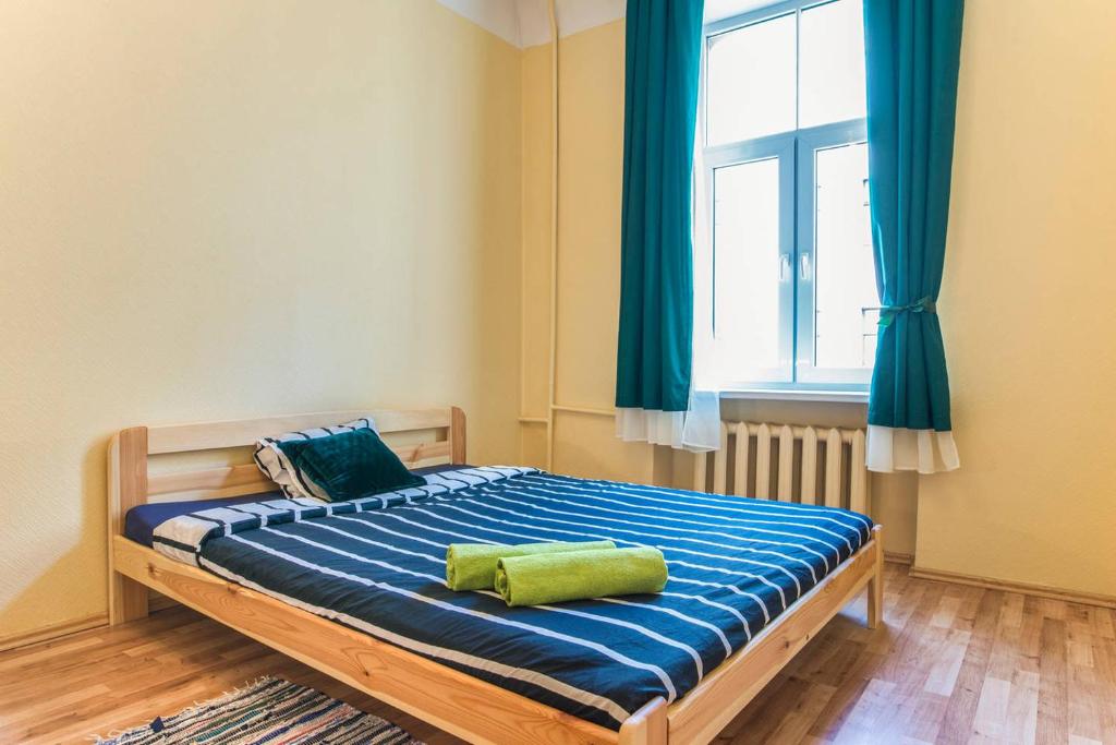 a bedroom with a bed with blue sheets and a window at Smart Cat Apartments in Riga