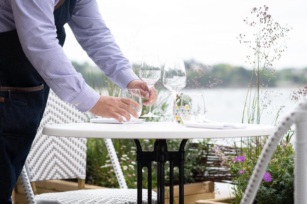 a person holding two wine glasses on a table at Hôtel De La Vallée in Dinard