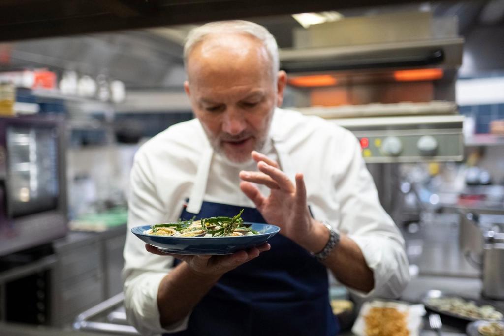 a man in a kitchen holding a plate of food at Hôtel De La Vallée in Dinard