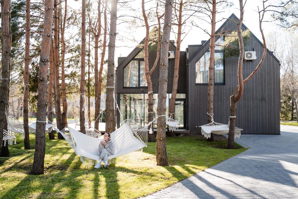 a woman sitting in a hammock in front of a house at Pasaka Palanga in Palanga