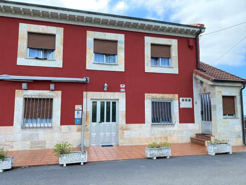 un edificio rojo con una puerta roja y ventanas en Casa Noval, zona rural VV-3120-AS, en Bimenes
