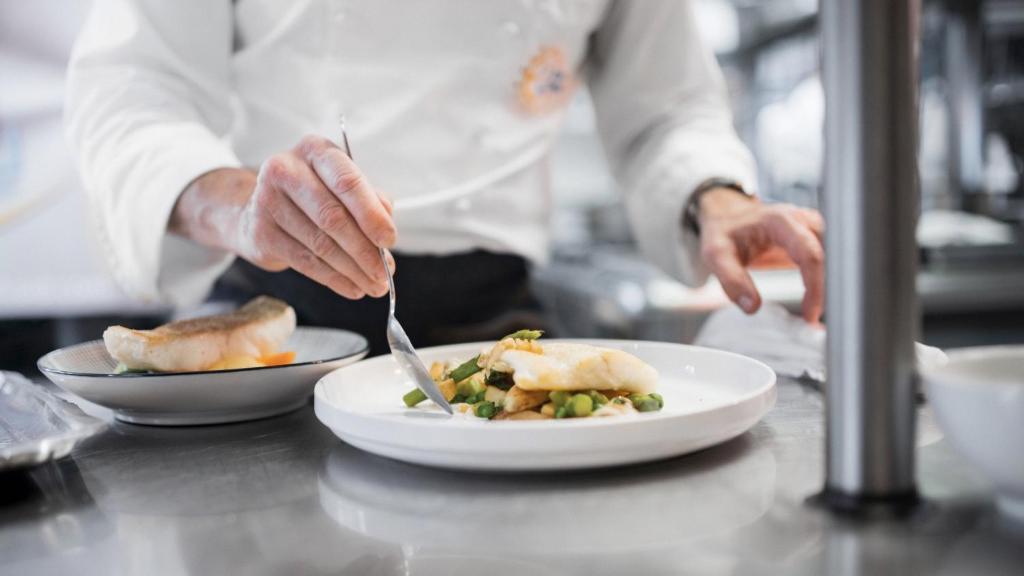 a chef preparing a plate of food on a counter at Hôtel De La Vallée in Dinard