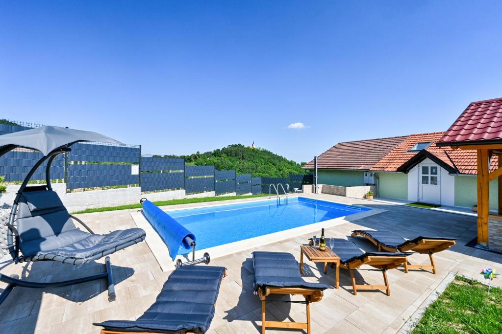 a swimming pool with chairs and an umbrella and a house at Kuća za odmor Tranquilo in Pregrada