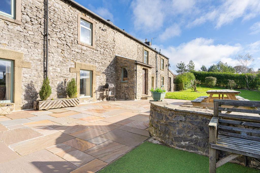 a stone house with a bench in front of it at Hulmes Vale House - Sleeps 14 - Peak district in Buxton