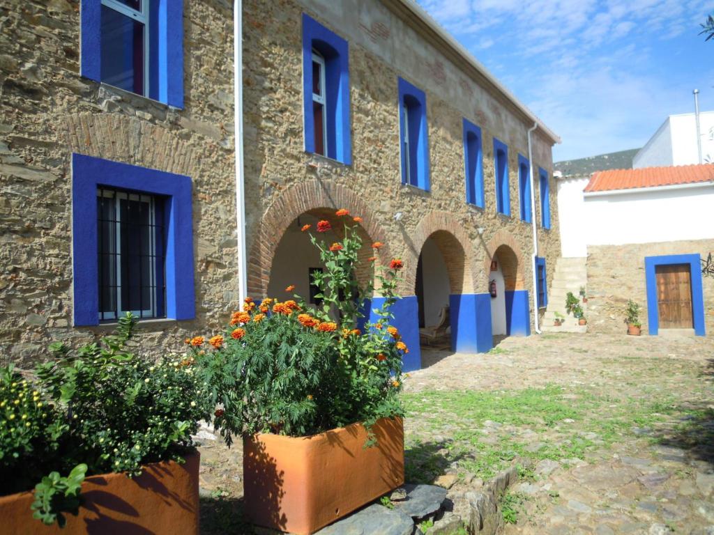 un edificio con ventanas azules y flores delante de él en Hostel Cañaveral, en Cañaveral