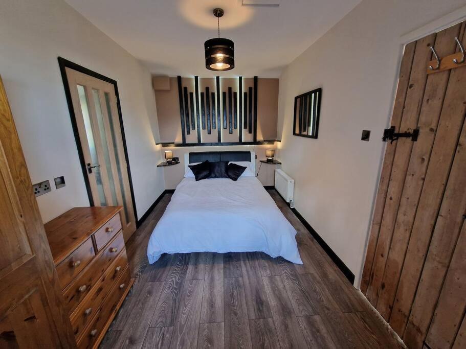 a bedroom with a white bed with a wooden floor at Swallows Nest in Abergavenny