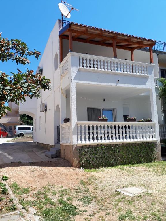 a white house with a balcony on the side of it at Apartman Zrno in Vodice