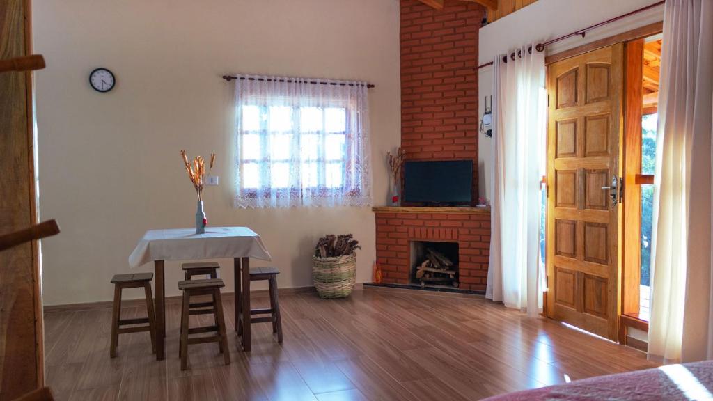 sala de estar con mesa, sillas y chimenea en Aconchegante chale com Wi Fi em Sapucai Mirim MG, en Gonçalves