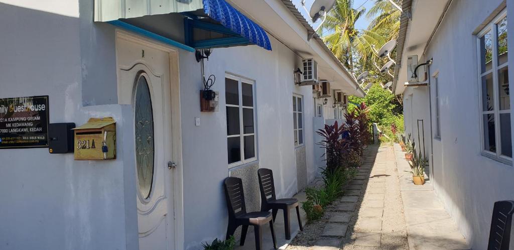 eine schmale Gasse mit zwei Stühlen neben einem Gebäude in der Unterkunft CHILY GUESTHOUSE LANGKAWI in Pantai Cenang