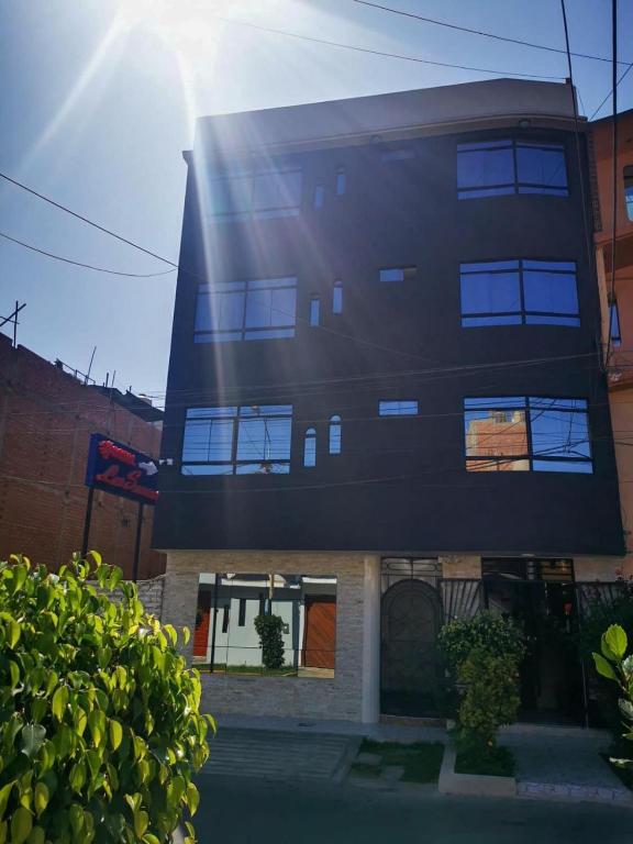een hoog zwart gebouw met de zon erachter bij Los Sauces in Huacho
