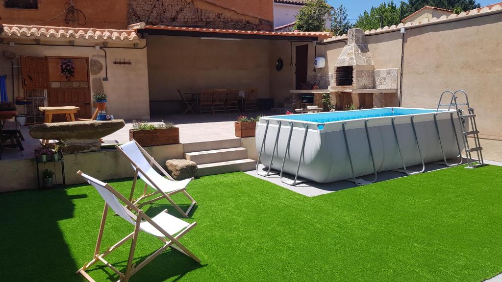 un patio con piscina y 2 sillas de césped en Casa Rural Rincón, en El Cabaco