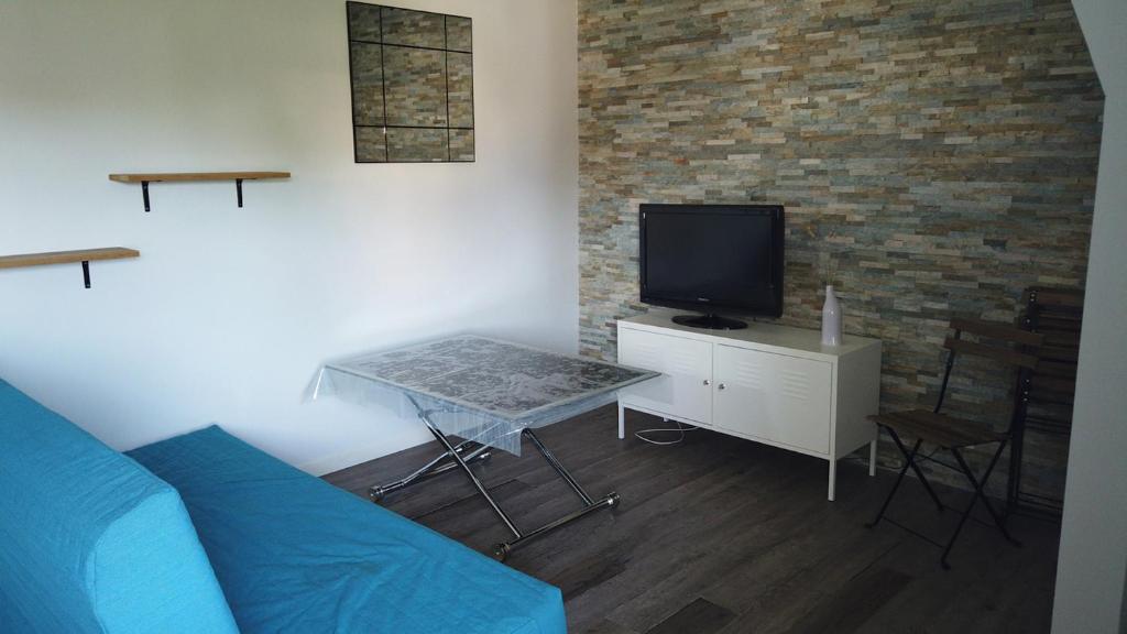 un salon avec un canapé bleu et une télévision dans l'établissement Appartement cosy à quelques mètres de la plage, à Pornichet