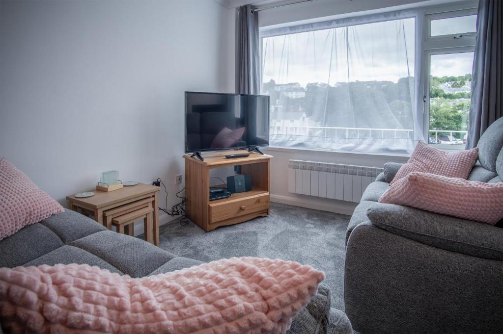 a living room with a couch and a tv at Harbour Court - 2 Bedroom Apartment - Saundersfoot in Saundersfoot