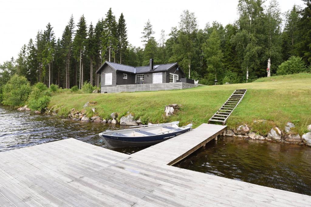 a boat is docked at a dock next to a house at Cozy holiday home with its own jetty and panoramic views of Norra Orsjon in Arvika