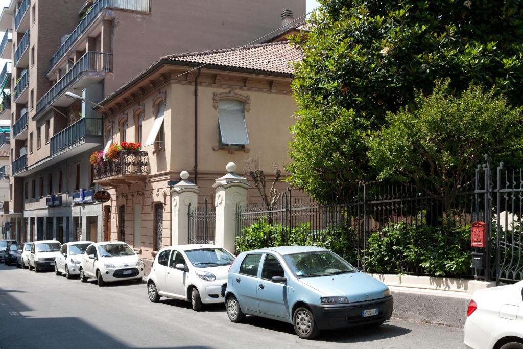 eine Reihe von Autos, die vor einem Gebäude geparkt sind in der Unterkunft B&B Casa Liberty in Acqui Terme
