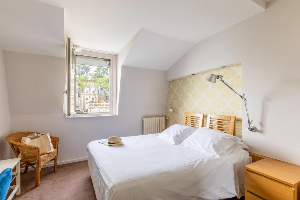 a bedroom with a white bed and a window at Hôtel De La Vallée in Dinard