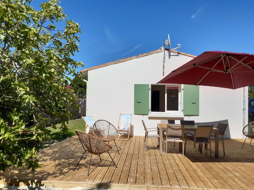 un patio con mesa, sillas y sombrilla en Charmante maison de plain pied avec 700m2 de jardin cloturé en Saint-Clément-des-Baleines