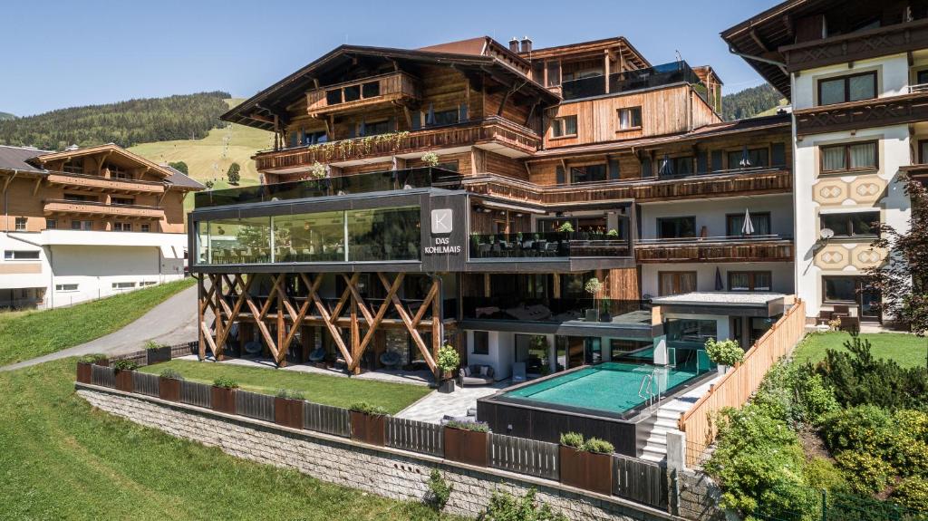 a large building with a swimming pool in front of it at Hotel Kohlmais in Saalbach-Hinterglemm