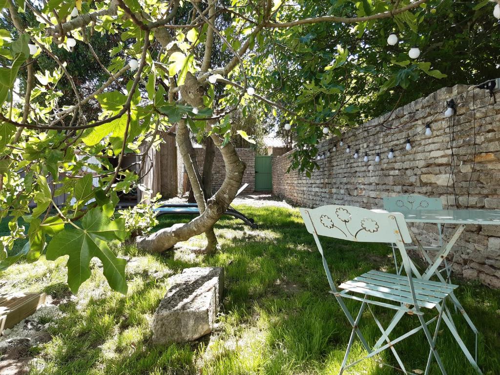 a chair sitting in the grass next to a brick wall at Charmante maison de plain pied avec 700m2 de jardin cloturé in Saint-Clément-des-Baleines