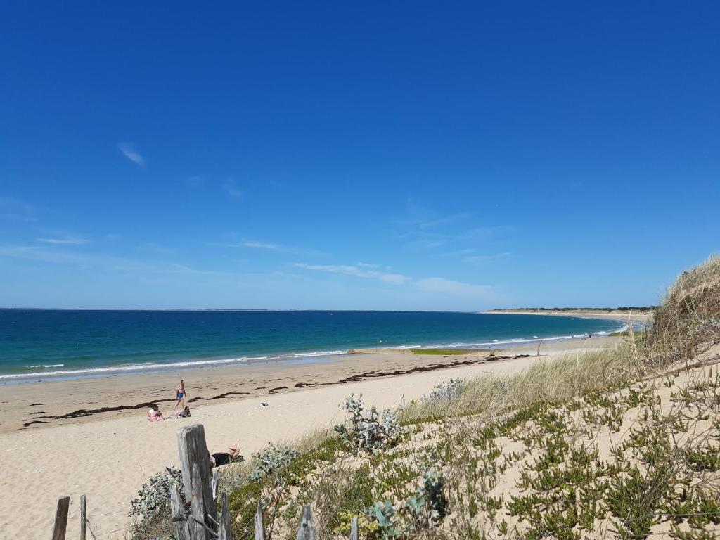 a beach with people on the sand and the ocean at Charmante maison de plain pied avec 700m2 de jardin cloturé in Saint-Clément-des-Baleines