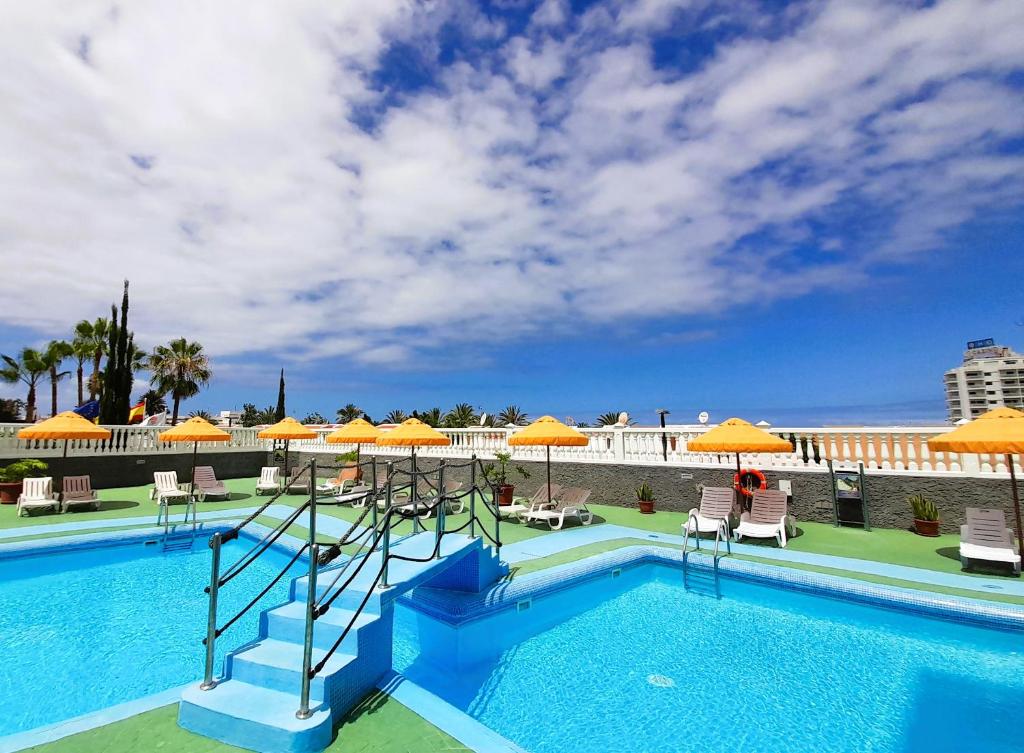 una piscina con ombrelloni e sedie arancioni di Olympia 425, See View Wifi Free a Playa de las Americas