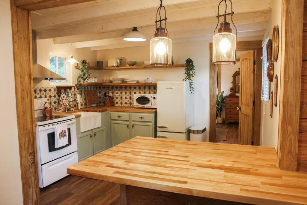 a kitchen with green cabinets and a wooden counter top at The Greenhouse Cozy Cottage- Walk to Downtown! in Opelika