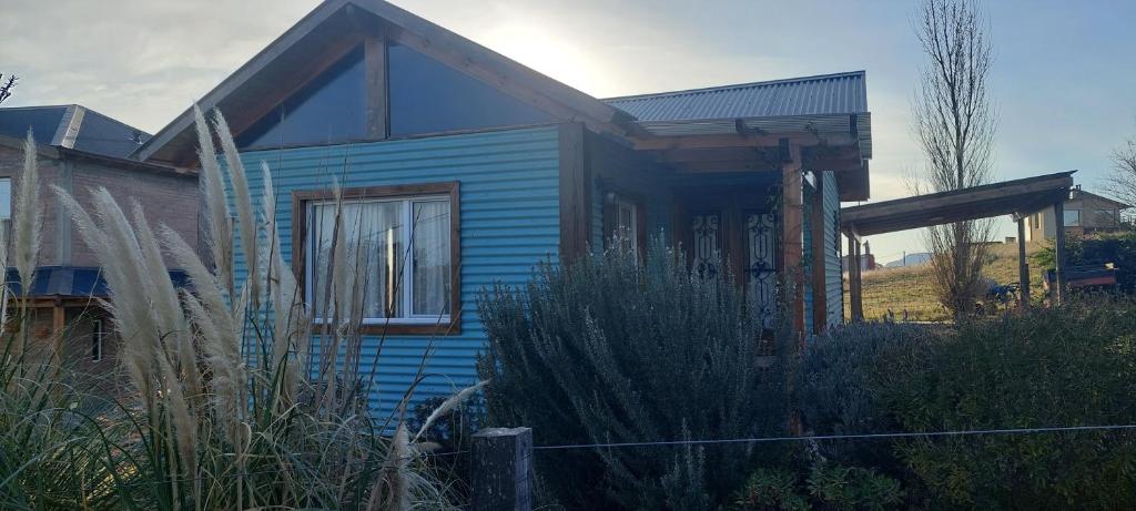 ein blaues Haus mit einem Zaun davor in der Unterkunft Cabaña El Pazo in Sierra de la Ventana