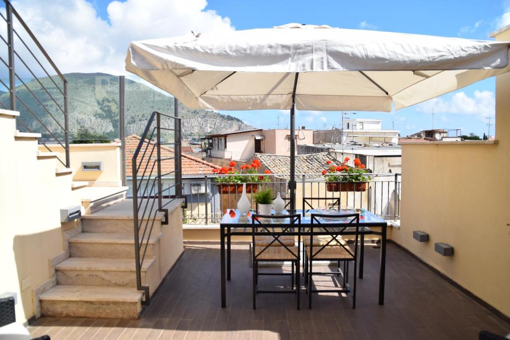 a table and chairs with an umbrella on a balcony at Palermo Holidays in Mondello