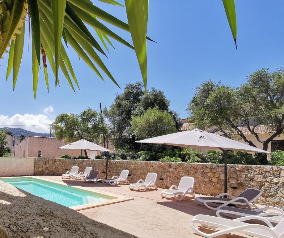 a group of chairs and umbrellas next to a swimming pool at Résidence Saint Michel in LʼÎle-Rousse