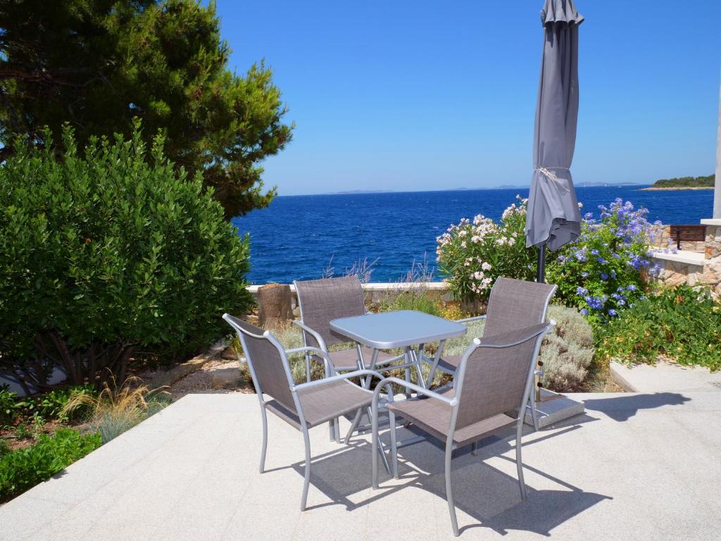 a table and chairs with an umbrella and the ocean at APARTMANI SMILJA in Primošten