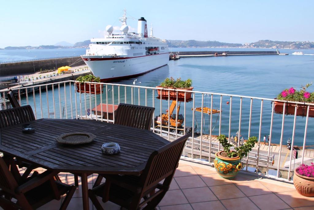 a balcony with a table and a cruise ship in the water at Sole Luna Mare in Pozzuoli
