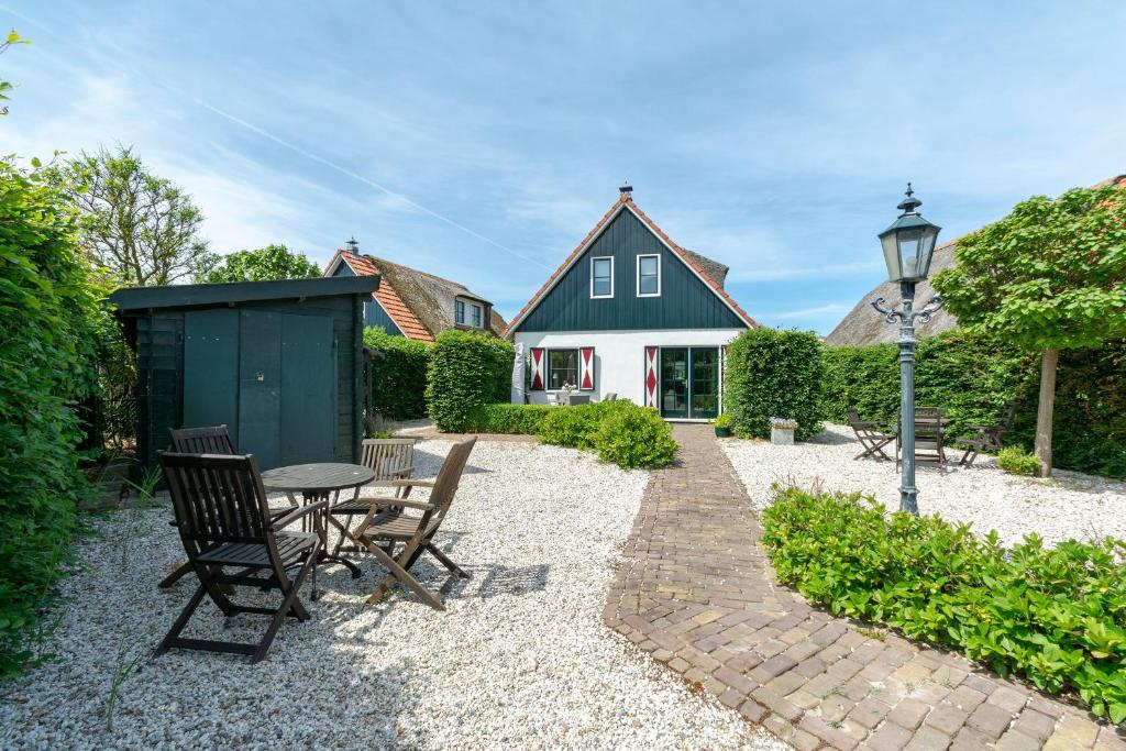 um jardim com mesa e cadeiras e uma casa em Buitenplaats 103 Callantsoog em Callantsoog