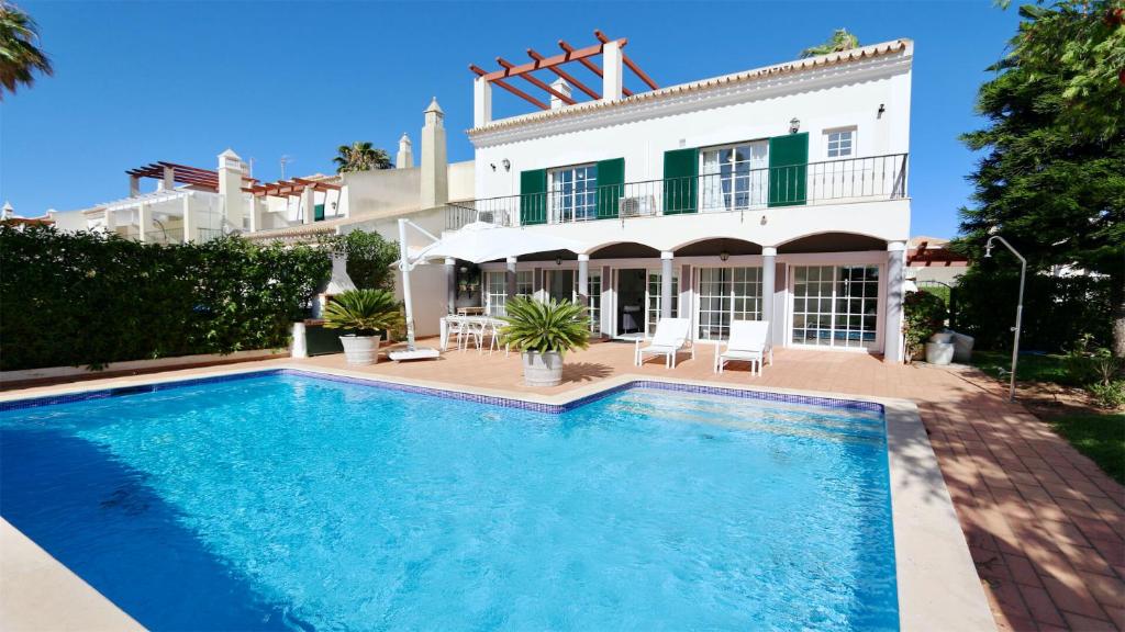 a villa with a swimming pool in front of a house at Vila Castro-Cleverdetails, Quiet area, private pool in Vilamoura