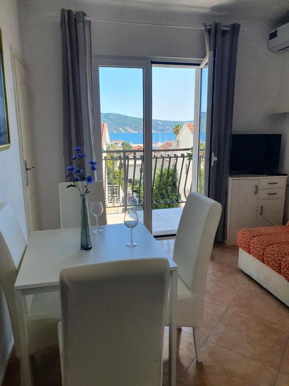 a dining room with a table and chairs and a balcony at Fortunella Apartments in Herceg-Novi