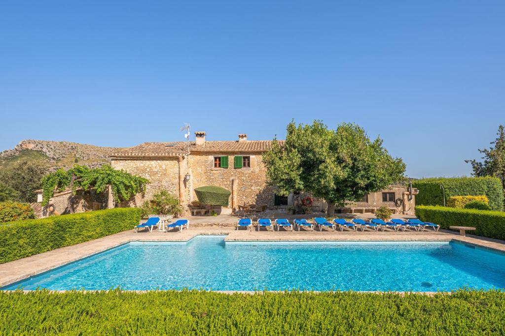 a swimming pool with chairs and a house at Can Faveta in Alcudia