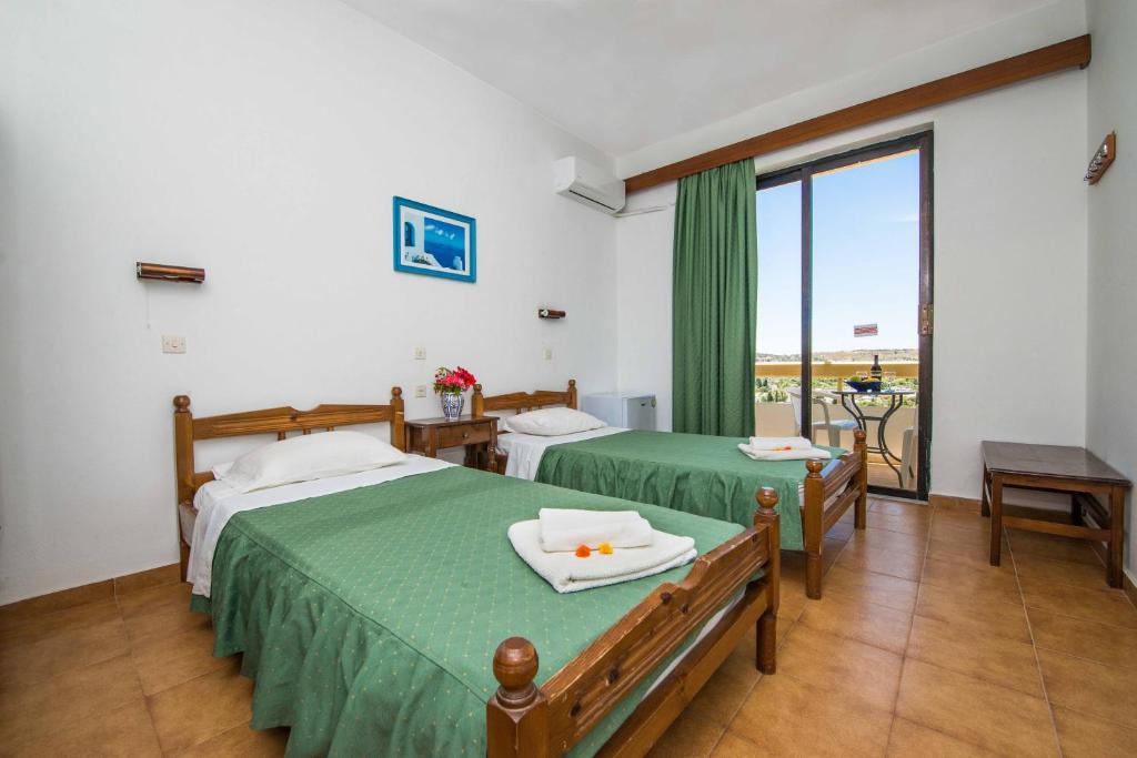 a hotel room with two beds and a balcony at Hotel Eleni Anagros in Archangelos