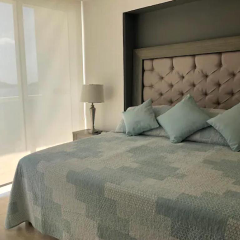 アカプルコにあるApartamento con Piscina Frente al Mar en Acapulcoのベッドルーム(青い枕の大型ベッド1台付)